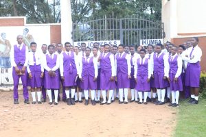 A large group of St. John's S.S - Ikumba students in purple uniforms assembled near the school campus entrance gate.